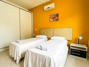two beds in a room with an orange wall at Aguas do Santinho Residence - Praia do Santinho in Florianópolis