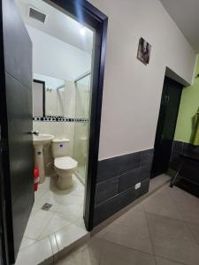baño con aseo y puerta de ducha de cristal en Hotel Laureles Home, en Medellín