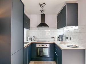 een keuken met blauwe kasten en een fornuis met oven bij Stylish Retreat for Your Short Getaway in Londen