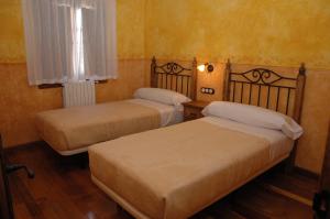 two beds in a room with yellow walls at Casa Rural las Médicas in Buendía