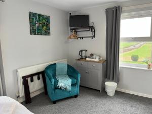 a bedroom with a blue chair and a window at The Island View in Berwick-Upon-Tweed