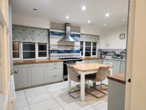 a kitchen with white cabinets and a table and chairs at Elmdon House with 4 Spacious Bedrooms to choose in Birmingham