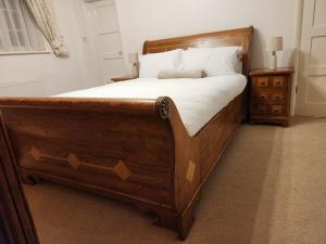 a wooden bed with white sheets and pillows at Elmdon House with 4 Spacious Bedrooms to choose in Birmingham