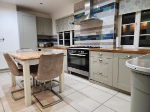 a kitchen with a wooden table and a stove at Elmdon House with 4 Spacious Bedrooms to choose in Birmingham