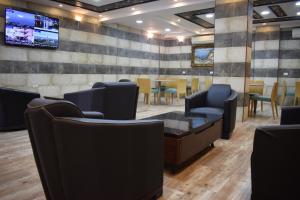 een wachtkamer met stoelen en een tv aan de muur bij Nour Hotel in Amman