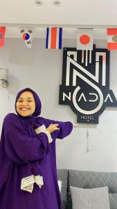 a woman in a purple robe standing in front of a sign at NADA _ HOTEL in Cairo