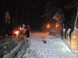 eine Gruppe von Menschen, die nachts im Schnee stehen in der Unterkunft Sosnowy Zakątek in Józefów