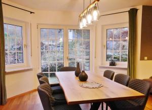 a dining room with a table and chairs and windows at First Class Domizil Großer Bergzauber inklusive MeineCardPlus in Willingen