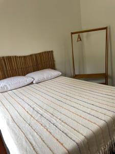 a bedroom with a bed with a striped blanket at Vila Guaraú in Peruíbe