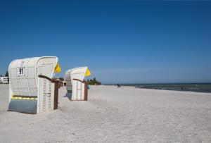 deux empilements de chaises sur une plage de sable dans l'établissement Penthouse "Ostsee-Himmelreich" Großenbrode, à Großenbrode