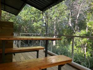 two benches on a deck with trees in the background at Techos Amarillos aparthotel in Fomento