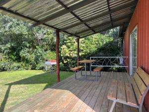 eine Veranda mit einer Holzterrasse mit einer Bank und einem Tisch in der Unterkunft Techos Amarillos aparthotel in Fomento