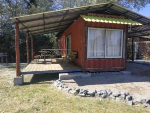 a red cabin with a deck with a table at Techos Amarillos aparthotel in Fomento
