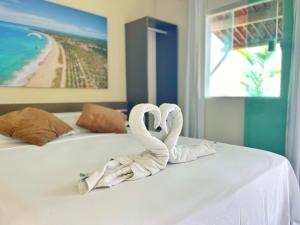 two swans made out of towels sitting on a bed at Pousada Ondas do Mar in Porto De Galinhas