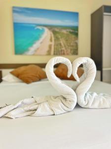 two swans shaped like hearts sitting on a bed at Pousada Ondas do Mar in Porto De Galinhas