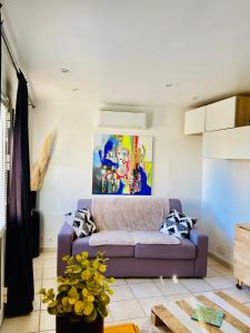 een woonkamer met een paarse bank en een schilderij bij Studio entre Aix en Provence et Marseille et parking in Septèmes-les-Vallons