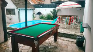 a pool table in front of a swimming pool at Praia Piscina Bilhar Churrasqueira in São Sebastião