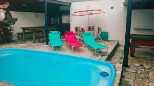a pool with chairs and a table and an umbrella at Praia Piscina Bilhar Churrasqueira in São Sebastião