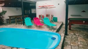 - une piscine avec des chaises, une table et un parasol dans l'établissement Praia Piscina Bilhar Churrasqueira, à São Sebastião