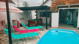 a pool with chairs and a table and an umbrella at Praia Piscina Bilhar Churrasqueira in São Sebastião