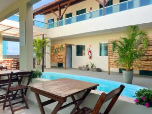 a patio with a table and chairs and a swimming pool at Pousada Ondas do Mar in Porto De Galinhas