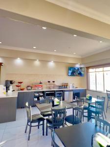 a restaurant with tables and chairs and a kitchen at Ramada by Wyndham in Quesnel