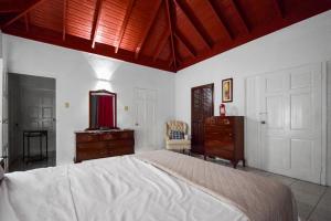 ein Schlafzimmer mit einem großen Bett, einer Kommode und einer Tür in der Unterkunft Harriott Heights in Mandeville