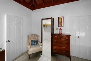 a room with a mirror and a chair and a dresser at Harriott Heights in Mandeville