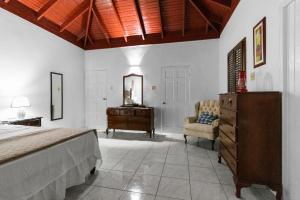 1 dormitorio con 1 cama, vestidor y silla en Harriott Heights en Mandeville