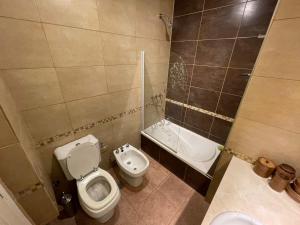 a bathroom with a toilet and a sink and a tub at Departamento Parque Necochea in Necochea