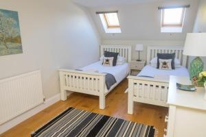 two beds in a white room with two windows at Entire Apartment in Central Brockenhurst in Brockenhurst