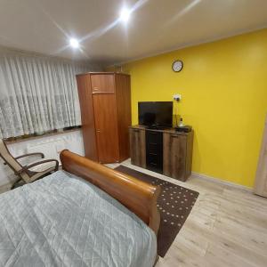 1 dormitorio con 1 cama, TV y pared amarilla en Sunstreet, en Lubin