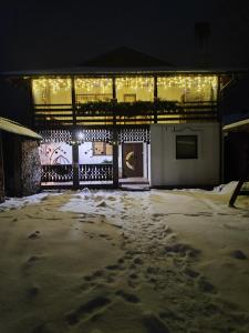 a building covered in snow at night with lights at Карпатський куточок in Slavske