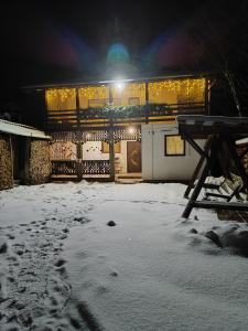 a building covered in snow at night with lights at Карпатський куточок in Slavske