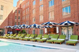 a row of chairs and umbrellas next to a pool at The Alida, Savannah, a Tribute Portfolio Hotel in Savannah
