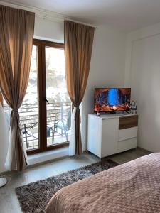 a bedroom with a television on a dresser with a window at Milmari N lux Sena in Kopaonik