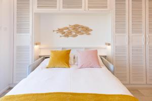 een slaapkamer met een wit bed en kleurrijke kussens bij La parenthèse - Studio vue Océan avec terrasse, plage Notre-Dame in Capbreton