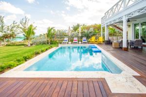 - une piscine dans un jardin avec une terrasse en bois dans l'établissement Wild Orchid home, à Governorʼs Harbour