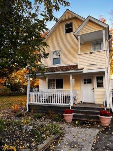 a yellow house with a white porch and stairs at Cozy Modern Farmhouse 2 Bedroom Apartment in Torrington