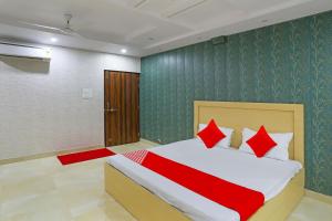 a bedroom with a bed with red pillows at OYO Flagship Guddan Banquet Hall in Kānpur