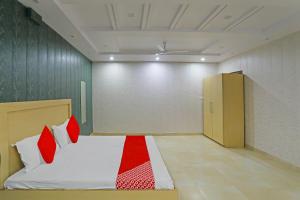 a bedroom with a bed with red and white pillows at OYO Flagship Guddan Banquet Hall in Kānpur