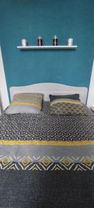 a bed with two pillows and a blue wall at Coquet 2 pièces proche de Paris in Bagnolet