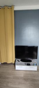 een flatscreen-tv in een kamer met een gordijn bij Coquet 2 pièces proche de Paris in Bagnolet
