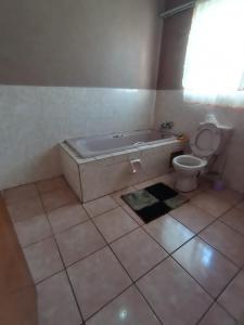 a bathroom with a tub next to a toilet at Nafi Guesthouse in Phuthaditjhaba