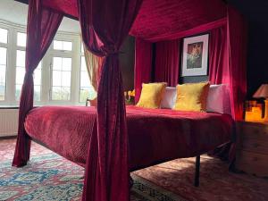 a bedroom with a canopy bed with red curtains at The Wizards House York - discounts for long stays in York