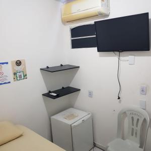 Habitación con aseo y TV en la pared. en Pousada Manaíra Buena Playa en João Pessoa
