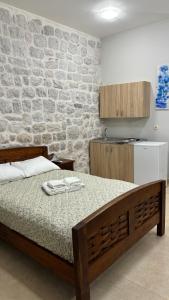 1 dormitorio con cama y pared de piedra en Filip Deluxe Rooms, en Kotor