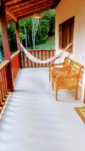 - une terrasse couverte avec 2 chaises et un hamac dans l'établissement Chalé Céu de Minas, à Visconde de Mauá