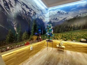 a room with a wall with a christmas tree and mountains at Stan SK in Pale