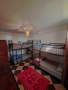 a room with four bunk beds and a checkered floor at taghazout life Guest House in Taghazout